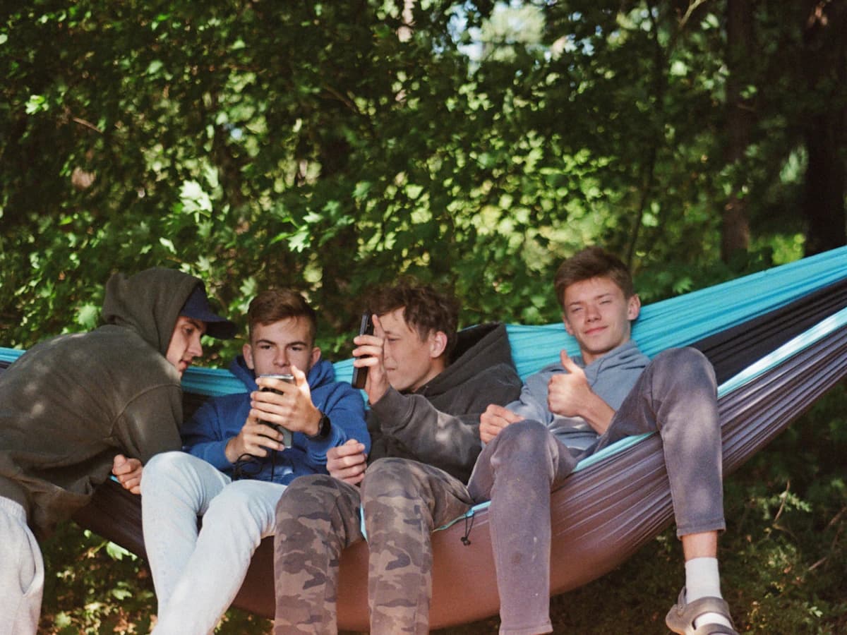 Friends relaxing in a hammock, reading on their phones